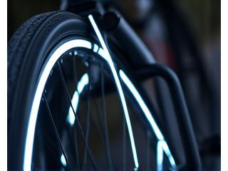 Close up of a bicycle wheel with reflective tape applied to spokes and rim
